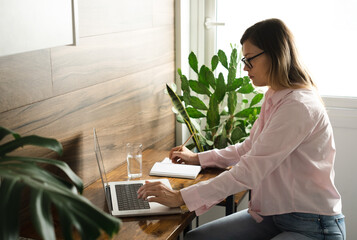 Serious middle-aged business woman wearing eyeglasses with long straight hair working at home...