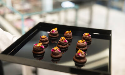 The waiter holds a Set of festive appetizer canapes on bread on a black tray as an event dish. Buffet table. Catering. Delicacy. Haute cuisine. 