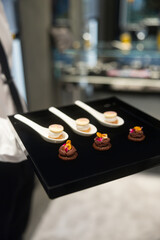 The waiter holds a Set of festive appetizer canapes on bread on a black tray as an event dish. Buffet table. Catering. Delicacy. Haute cuisine. 
