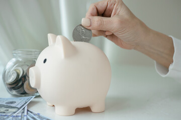 Close-up, Women hand putting coin in white piggy bank