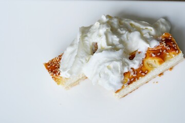 closeup full teaspoon of sour cream is laid out on curd casserole pie sprinkled with sesame seeds...