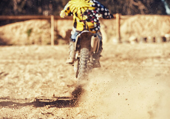 Naklejka na ściany i meble Time to rip up this track. motocross rider with a trail of dust behind him.