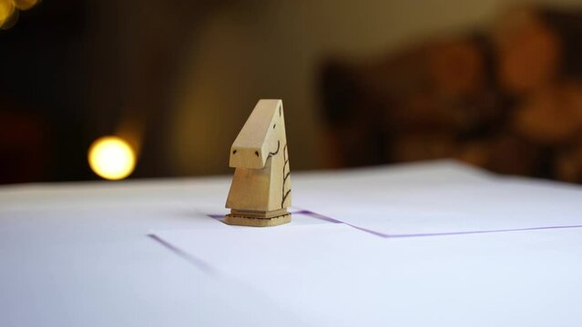 Wooden carved chess piece horse, knight spinning on white table