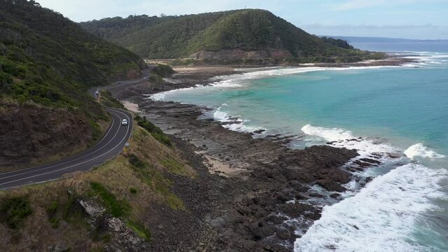 Car drives around corner of Great Ocean Road near Lorne, Victoria, Australia