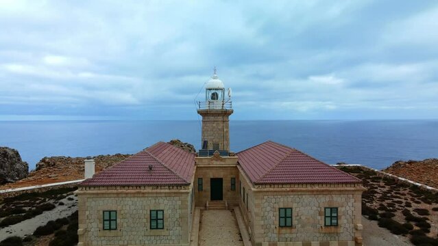 Flying over Punta Nati lighthouse in Menorca Spain. Old stone building with history.