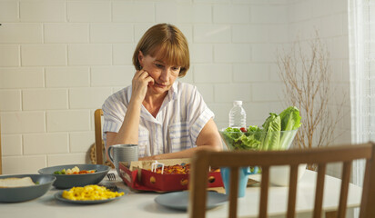 Elderly retired grandmother stay at home with unhappy face sitting alone on eating table in house....