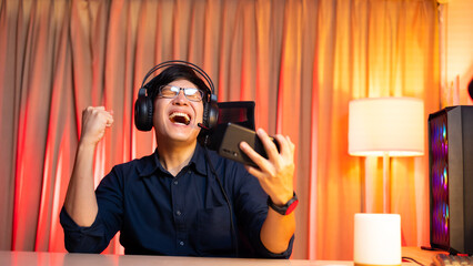 Esport online games. Happy and excited asian man gamer playing online game on smartphone. Colorful neon light room. Esport online game. © NVB Stocker