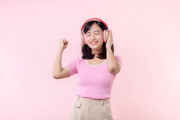 Obraz na płótnie Canvas Smile pretty model person listen music song and enjoy dance with wireless headphone online audio radio sound. Positive fun exited joyful youth female woman sing on pink isolated background studio
