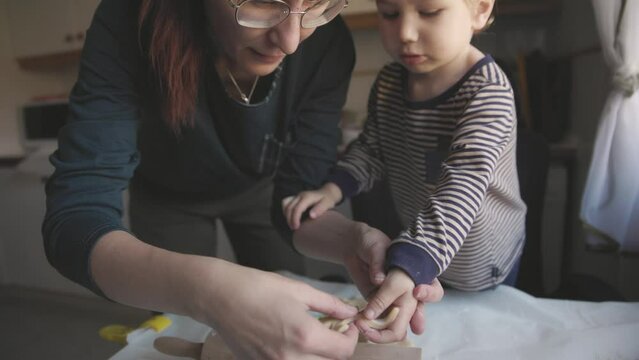 Family cooking - mother and son lay out raw blanks of dough on a baking sheet