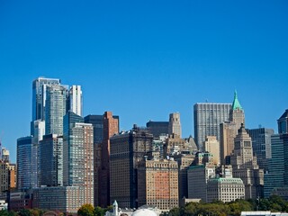 Obraz premium Looking back on Manhattan from the Hudson River and Liberty Island, as the towering high rises of Lower Manhattan loom above the river