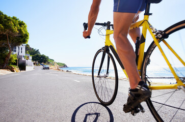 Enjoying the scenery while exercising. Cropped view of a cyclist cycling along an ocean road.