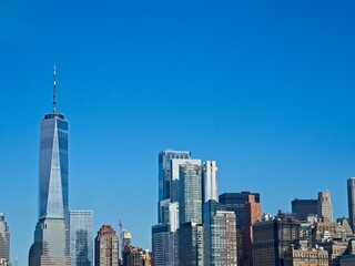 Obraz premium Looking back on Manhattan from the Hudson River and Liberty Island, as the towering high rises of Lower Manhattan loom above the river