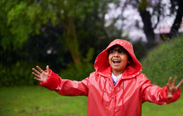 Always playing come rain or shine. a little boy wearing a raincoat playing outside.