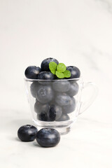 Fresh blueberries with mint leaves. The fruits are actual berries with many tiny seeds and are deep...