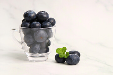 Fresh blueberries with mint leaves. The fruits are actual berries with many tiny seeds and are deep indigo to black color when ripe. Copy space.