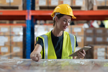 Caucasian female warehouse worker working at work checks stock, inventory with tablet on shelf pallet in the storage warehouse - obrazy, fototapety, plakaty
