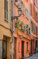 Fototapeta na wymiar Facades of traditional mediterranean houses with flower pots in the streets Old Town of Nice, France