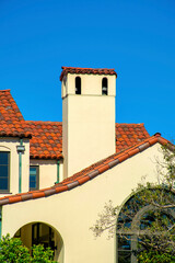 Obraz premium White house facade exterior with red or orange roof tiles and front yard trees in downtown modern neighborhood