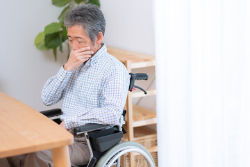 車椅子に乗った考えるシニア男性（介護・福祉）