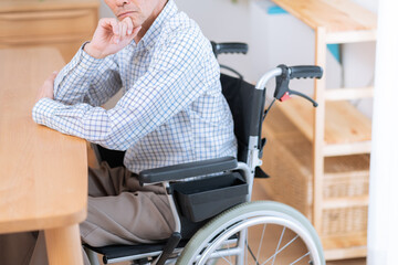 車椅子に乗った考えるシニア男性（介護・福祉）