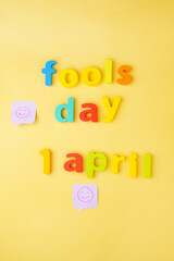 Concept of Happy 1 april Fools day. Yellow background, top view. Vertical photo