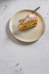 sliced of homemade Victoria sponge cake decorate with icing sugar on top in ceramic plate.
