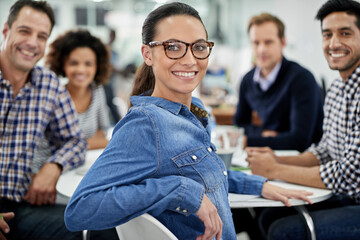 Feeling good about my office community. Relaxed businesswoman smiling at the camera with her colleagues at a meeting table.