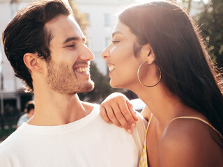 Smiling beautiful woman and her handsome boyfriend. Happy cheerful family. Sexy couple posing in the street at sunrise. During romantic date at sunny summer day outdoors. Looking at each other