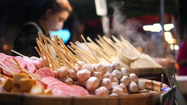 Local Asian Street Food: Traditional Thai BBQ Sausages and Fish Ball Satay at Night Market. High Quality 4K Slow Motion Cinematic Foodie Concept Footage. Bangkok, Thailand.