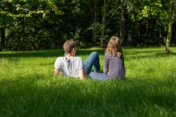 two people, friends are resting in the park on the grass