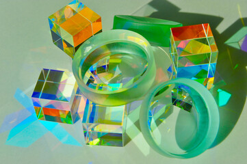 Closeup of convex and concave lens placed on top of dichroic cube prism, dispersing ray of light into spectrum colours, refraction and reflection create colourful shade and shadow on white paper