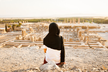 Tourist woman visit famous destination sit on viewpoint above Persepolis. Explore famous historical...