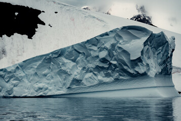 Fototapeta na wymiar Massive Iceberg In Antarctica Looks Textured and Chiseled, Unique Shapes, Moody Landscape Shot