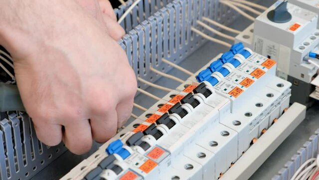 Electrical engineer assembles the mounting panel. Installing cables with the tip with a screwdriver to the contactor,tightening the nut in the control cabinet.