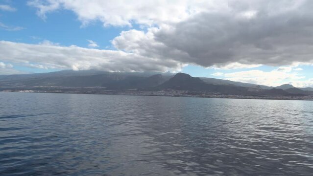 Tenerife Island As Seen From A Feribot In The Summer With Blue Sky And Thick White Clouds, Spain