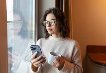 woman using phone with coffee cup at home