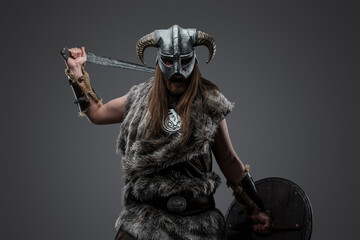 Shot of furious vandal from north dressed in helmet and fur holding sword and shield.