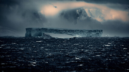 Fototapeta na wymiar Scenic Landscape of Huge Rectangular Iceberg In Antarctica Shows Signs of Calving, Moody and Misty