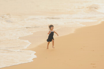 very happy time of cute girl in dress black run play on the beach with blur background beautiful sunset in the sea