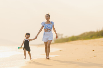 happy time of mom and daughter in dress black walking and run play on the beach with blur background beautiful sunset light in the sea