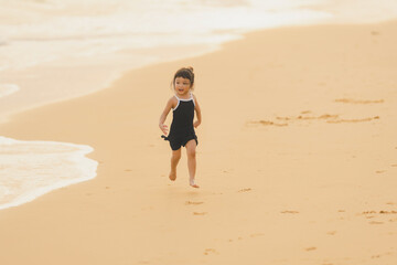 very happy time of cute girl in dress black run play on the beach with blur background beautiful sunset in the sea