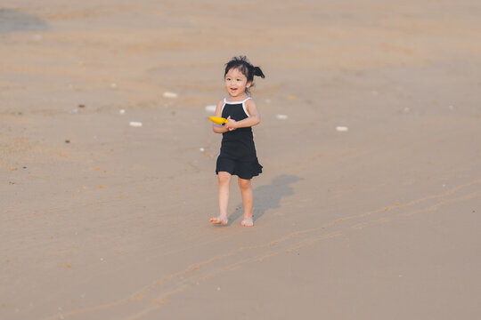 very happy time of cute girl in dress black run play on the beach with blur background beautiful sunset light in the sea