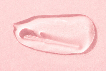 Smear of transparent cosmetic texture on a pink background top view. Gel product, serum macro.