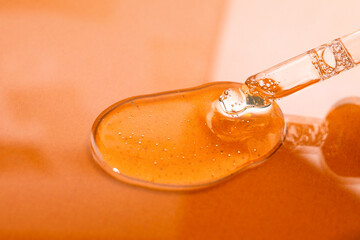 Dropper with a comet liquid product on an orange background. Means for dermatology and cosmetology,...