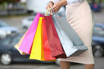 Women hands hold multicolored shopping bags closeup