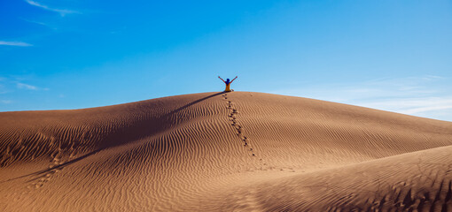 Happy woman with arms outstretched in the sahara desert ,  footprint in the sand dune