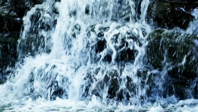 Raging rapids waterfall forcing down on the edge of the rock. Crystal clear water falls on the cliff. Hazy majestic waterfall river rapids