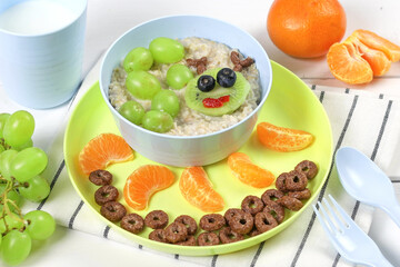 Funny bowl of oatmeal with fruits and berries caterpillar on a white wooden background. Food idea for kids, top view.
