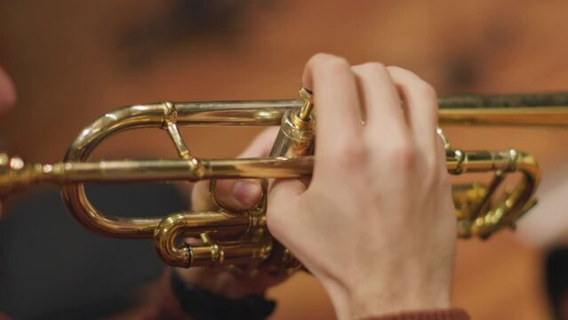 A slow motion video of a musician playing the C trumpet during a classical symphony orchestra rehearsal