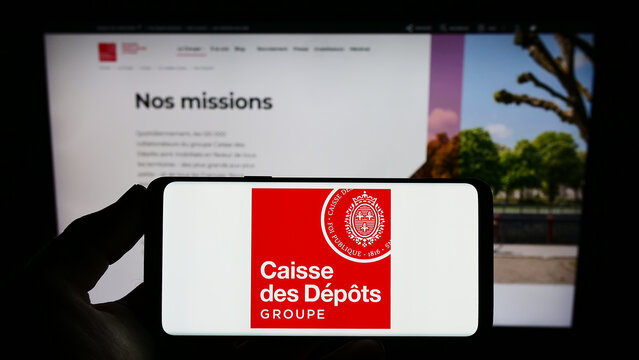 Stuttgart, Germany - 03-12-2023: Person holding smartphone with logo of Caisse des Depots et Consignations (CDC) on screen in front of website. Focus on phone display.